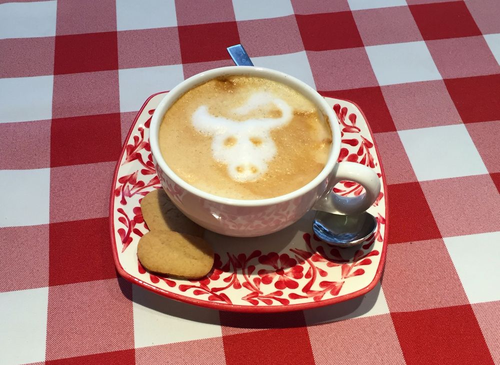 Capuchino con arte latte sobre mantel de cuadros